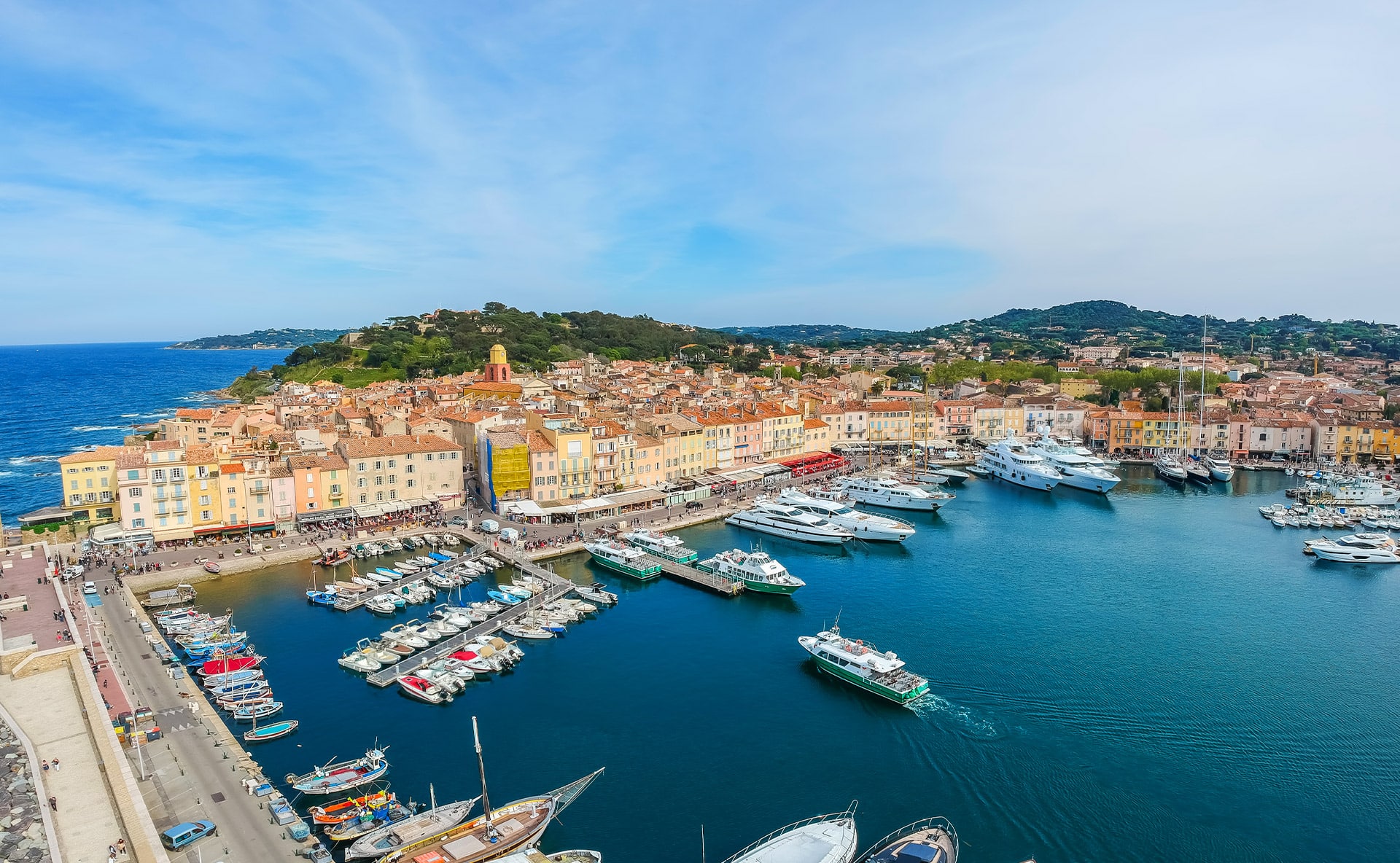 Boats in Saint-Tropez harbor beside colorful waterfront buildings.